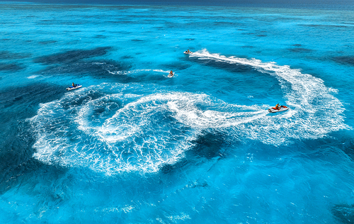 Aerial view of floating water scooter in blue water at sunny day in summer. Holiday in Indian ocean, Zanzibar, Africa. Top view of jet ski in motion. Tropical seascape with moving motorboat. Boats