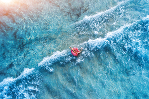 aerial view of a young woman swimming with the pink donut swim ring in the clear blue sea with beautiful waves at  in summer. tropical aerial landscape with girl, azure water. top view. travel
