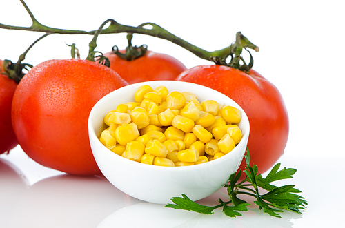 Corn grains on bowl and cherry tomatoes vine on white background.