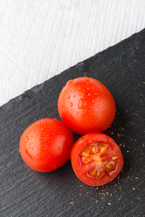 Fresh ripe cherry tomatoes on black ardoise tray.