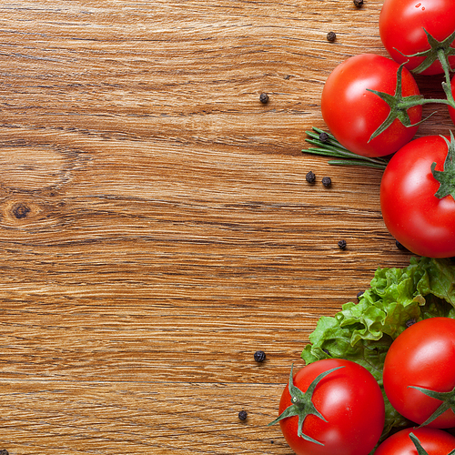 red tomatoes with green salad on wooden background