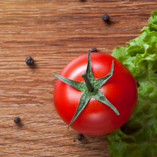 red tomato with green salad on wooden background