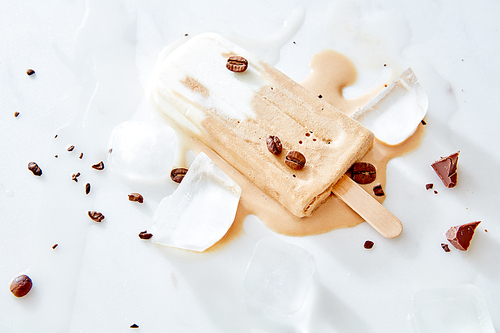 Coffee sorbet with coffee beans and piece chocolate on a marble ice background, top view. Summer delicious background