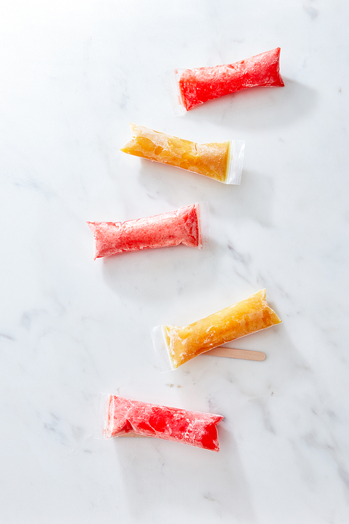 Ice candy plastic bags on marble background. Perfect desserts for homemade freezer pops. Healthy summer dessert