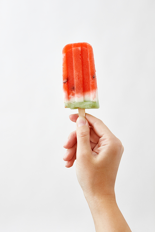 Hands of a girl holding appetizing, fresh slices of watermelon on a stick on a white background. The concept of healthy homemade ice popsicle with space for text . Summer dessert