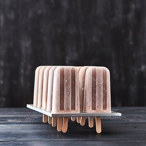 Coffee natural homemade ice-cream lolly in plastic forms on a black wooden table with space for text. Cold summer dessert