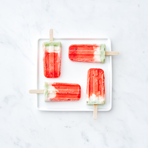 Ice lolly. Homemade ice cream in the form of a square in a white plate on a gray marble background with space for text. Sweet summer dessert. Flat lay