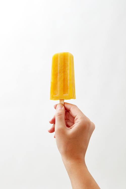 Cold natural yoghurt ice popsicle , holds a female hand on a white background with space for text. A photo can be used for your business ideas