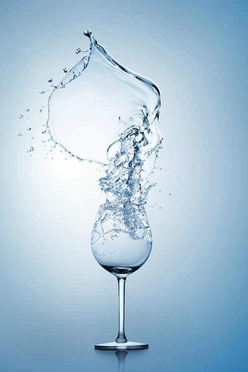 Water splashing out of a tall wine glass.