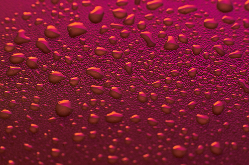Pink water drops background with yellow reflections.