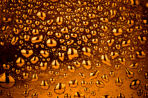Golden liquid drops on black background.