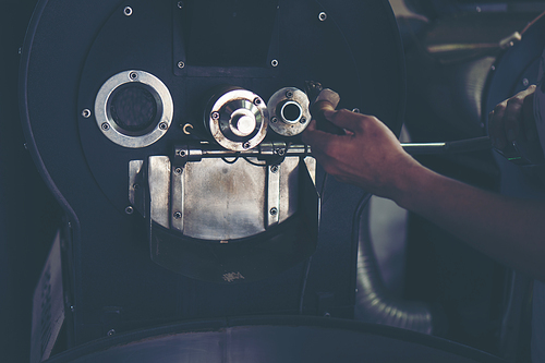 hand holding a probe of fresh roasted coffee beans in vintage filter image