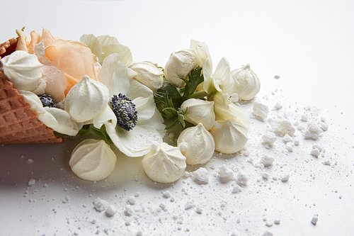 Ice cream of white flowers in waffle cone with meringues on white background from above, flat lay styling