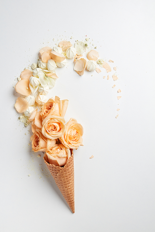 Waffle cone with composition of flowers on a white background , flat lay