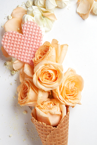 Waffle cone with composition of flowers and waffle heart on white background