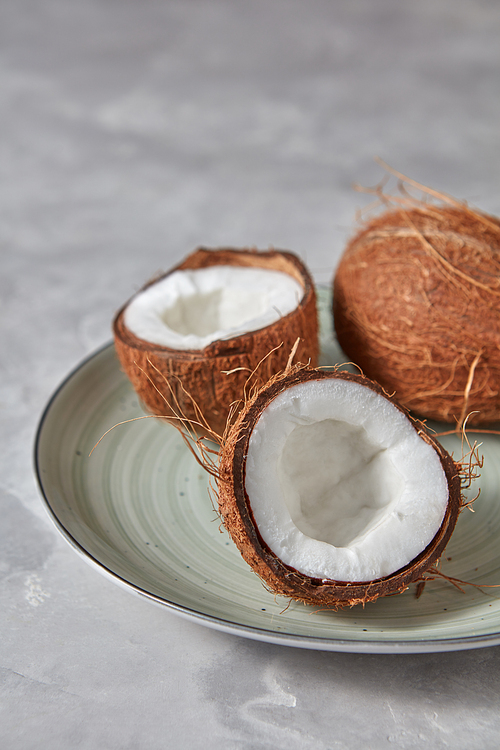 Exotic tropical fruit coconut on a plate on a gray stone background with copy space.