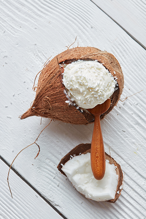 Coconut ice cream in shell of coconut in a wooden spoon flat lay