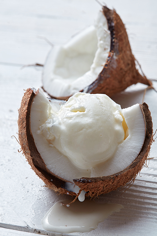 Vanilla coconut ice cream in shell of coconut on a wooden white background