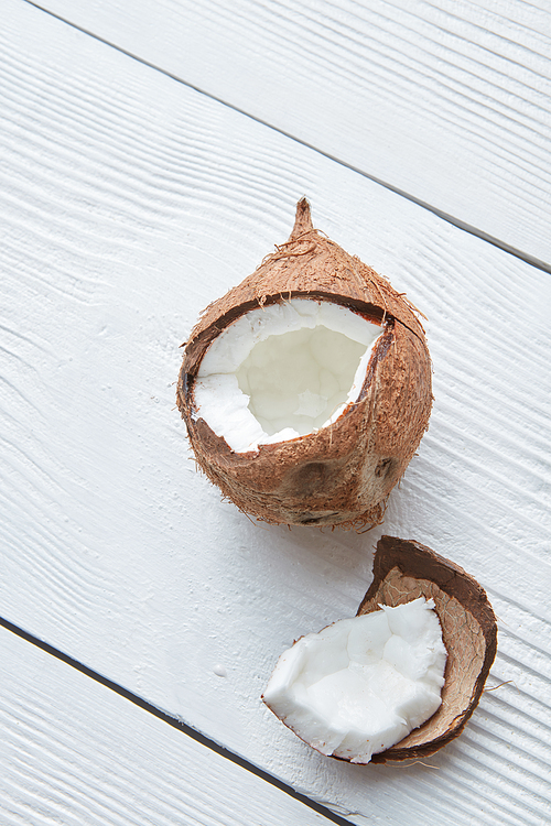 Broken raw ripe coconut isolated on white wooden background