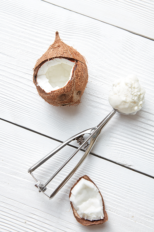 Scoop with coconut ice cream on a light wooden background