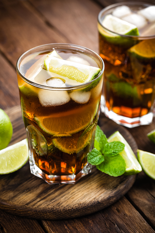 Cuba Libre cocktail with cola, lime and ice in glass, cold longdrink