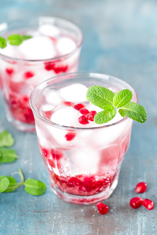 Infused water made of fresh pomegranate and mineral water with ice, cold refreshing and detox drink