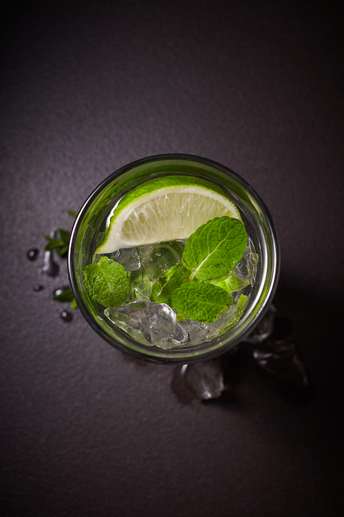 Mojito cocktail with lime and mint. in glass on dark stone table. Top view with space for your text