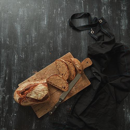 Flat lay On a dark background Sliced bread on a cutting board with a knife. Space for text