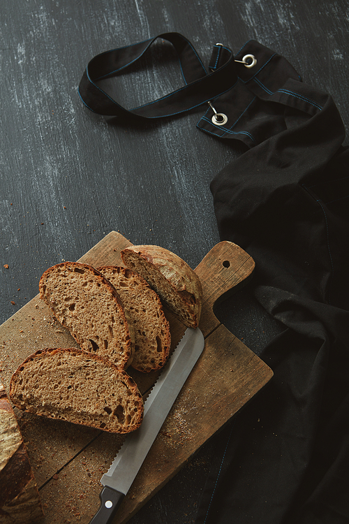 Sliced fresh bread with a knife on the kitchen board Background blurred flat lay