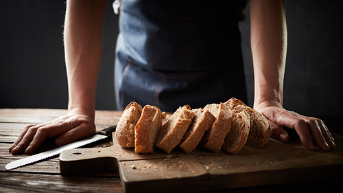 Whole grain bread put on a kitchen plate with a chef, knife lies next. Fresh bread on table close-up. Fresh bread on the kitchen table The healthy eating and traditional bakery concept