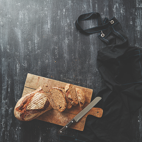 Sliced fresh bread with a knife on the kitchen board Background blurred flat lay