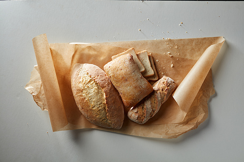 Assortment of different types of bread on paper on a gray background