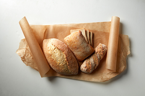 Different kinds of bread represented over cooking paper over white background. Range of different sorts of bread for your choice.