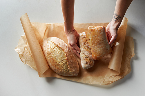 View from above of Human hands putting fresh bread on baking paper