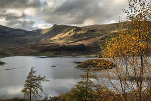 Epic Autumn Fall landscape of Hawes Water with epic lighting and dramatic sunlight in Lake District