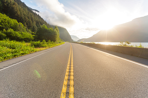 Scenic road in the mountains. Travel background. Man going on sunrise background.