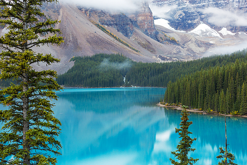 Serene scene by the mountain lake in Canada with reflection of the rocks in the calm water.