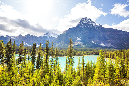 Serene scene by the mountain lake in Canada with reflection of the rocks in the calm water.