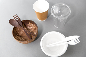 recycling, environment and eco friendly concept - close up of natural coconut bowl with wooden spoon and fork and plastic dishes on table
