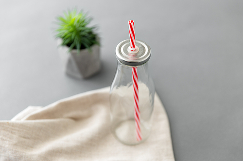 eco friendly concept - empty reusable glass bottle of with striped straw