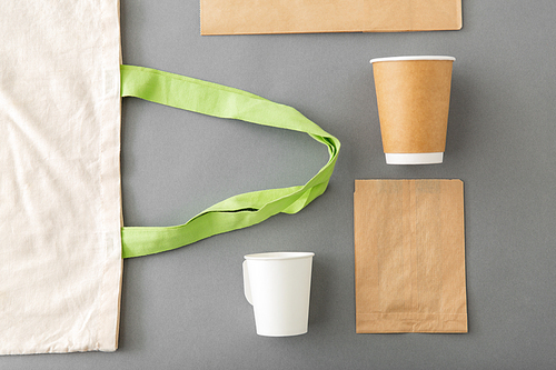 food and drink packaging, recycling and reuse concept - takeaway paper coffee cups and canvas shopping bag on grey background