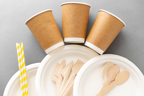 recycling, tableware and eco friendly concept - disposable dishes of paper and wood on grey background