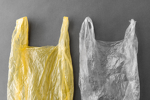 consumerism, recycling and environment concept - two disposable plastic bags on grey background