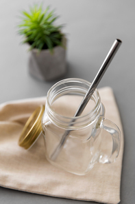 eco friendly concept - empty glass mug of with reusable metallic straw