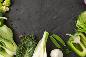 food, culinary and healthy eating concept - close up of different green vegetables on slate stone background