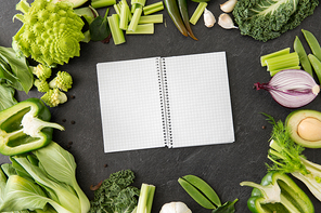 food, diet and healthy eating concept - close up of different green vegetables and diary with empty pages on slate stone background