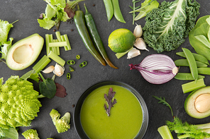food, culinary and healthy eating concept - close up of different green vegetables and cream soup in ceramic bowl on slate stone background
