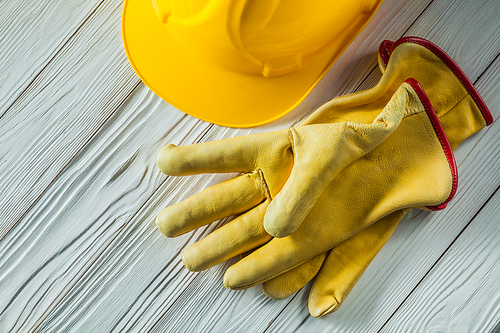 construction gloves and yellow helmet on vintage white painted wooden boards