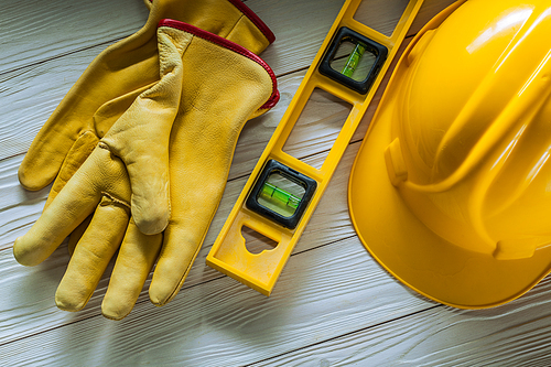 construction tools yellow helmet level and working gloves on wvintage painted white wood boards