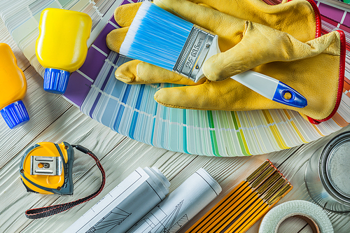 paint brush in working gloves with any other construction tools on white wood boards